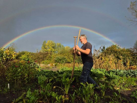 foto van tuinleider pieter en de regenboog op de achtergrond